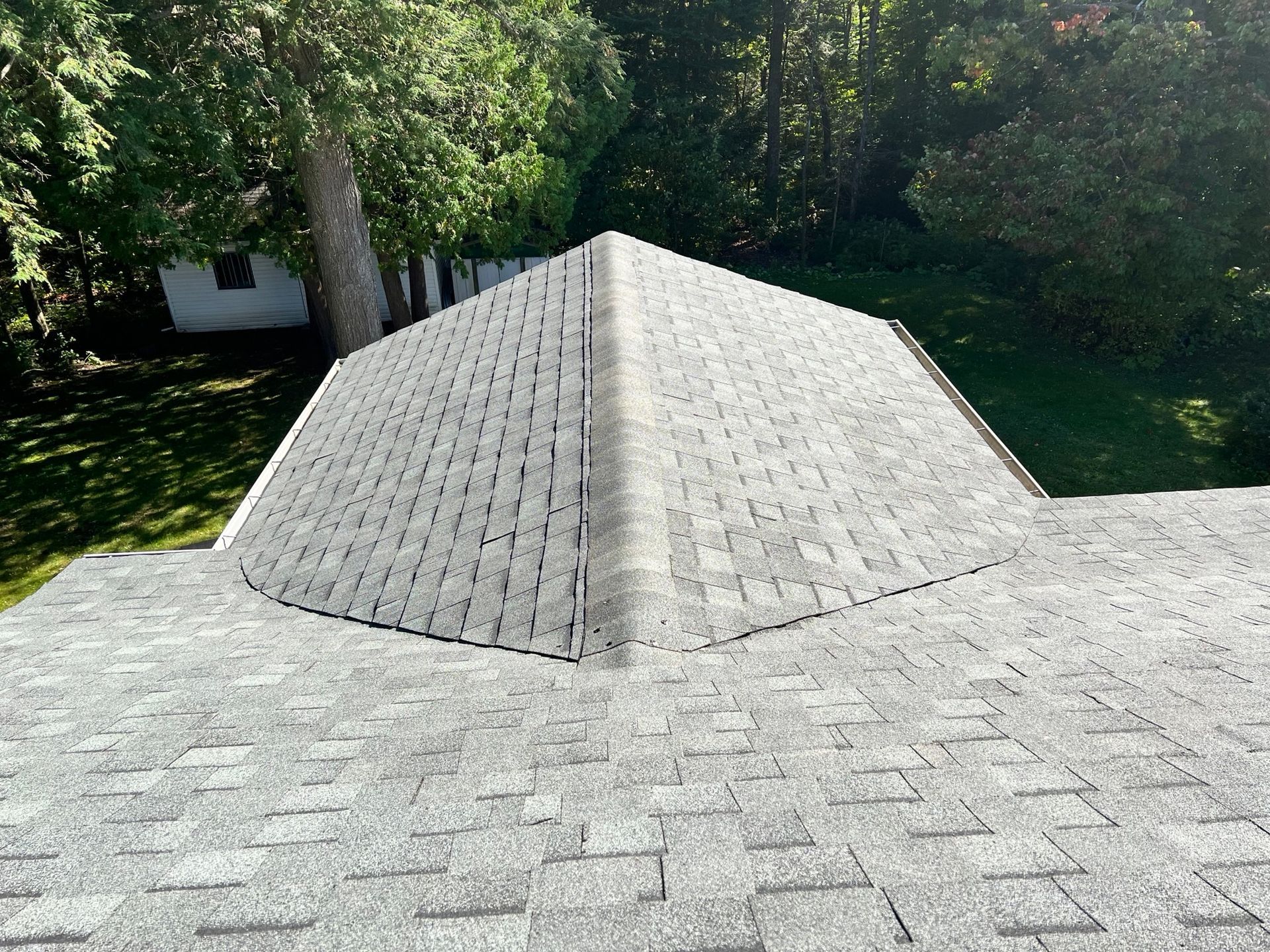 Toiture en bardeaux d'asphalte gris sur une maison, avec une section en pente.
