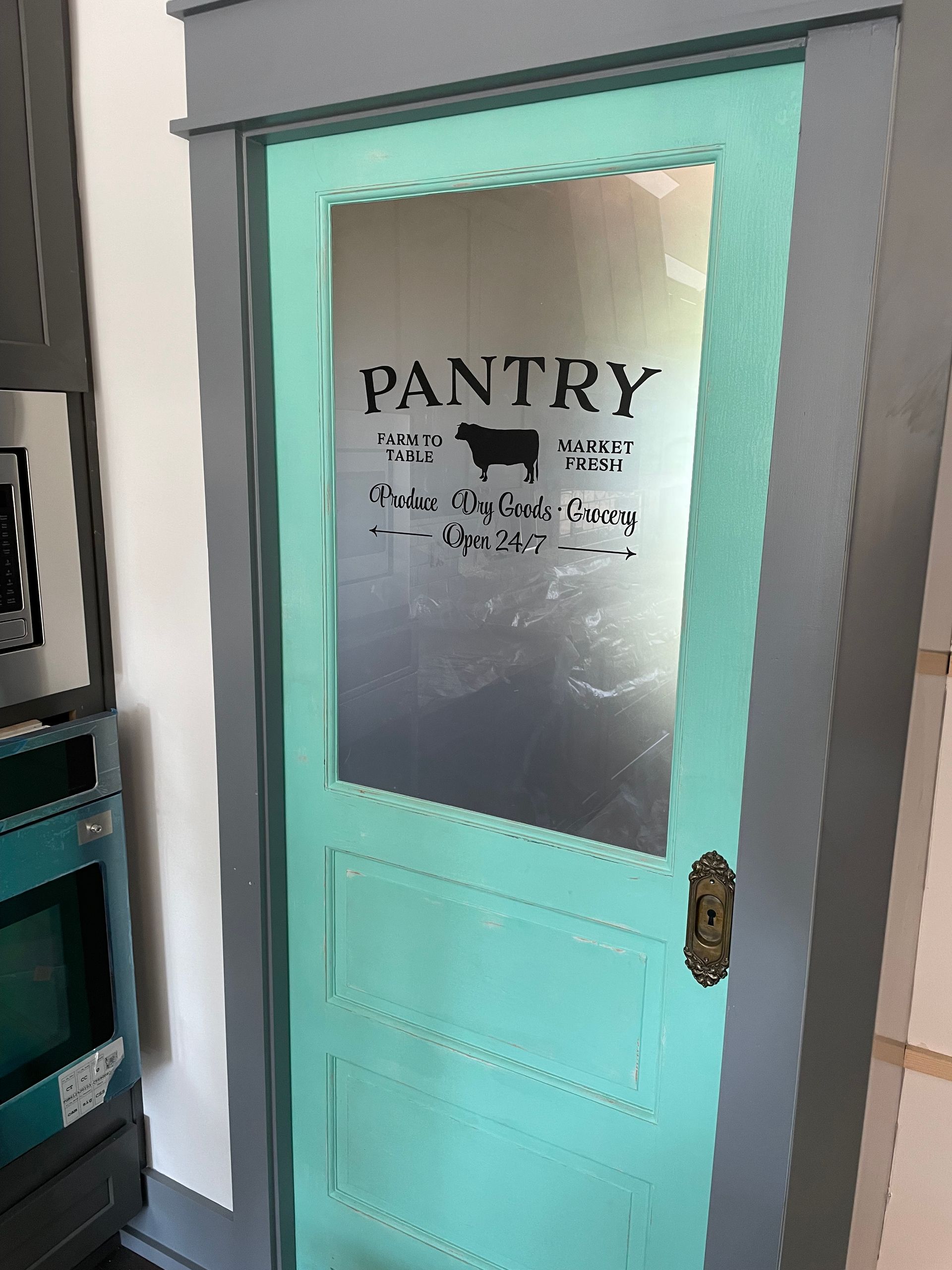A blue pantry door with a stencil on it.