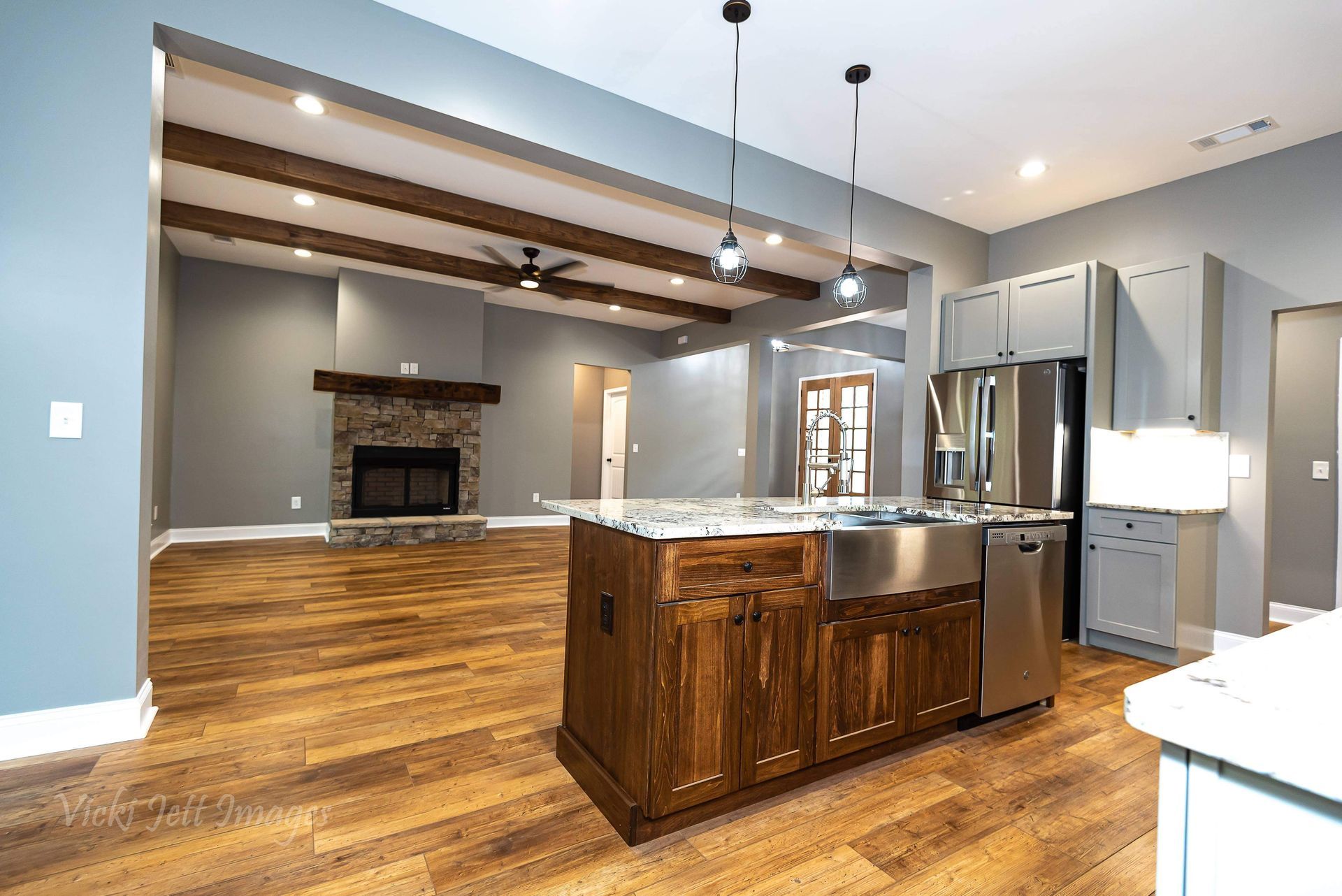 A kitchen with a large island , stainless steel appliances , wooden cabinets and a fireplace.