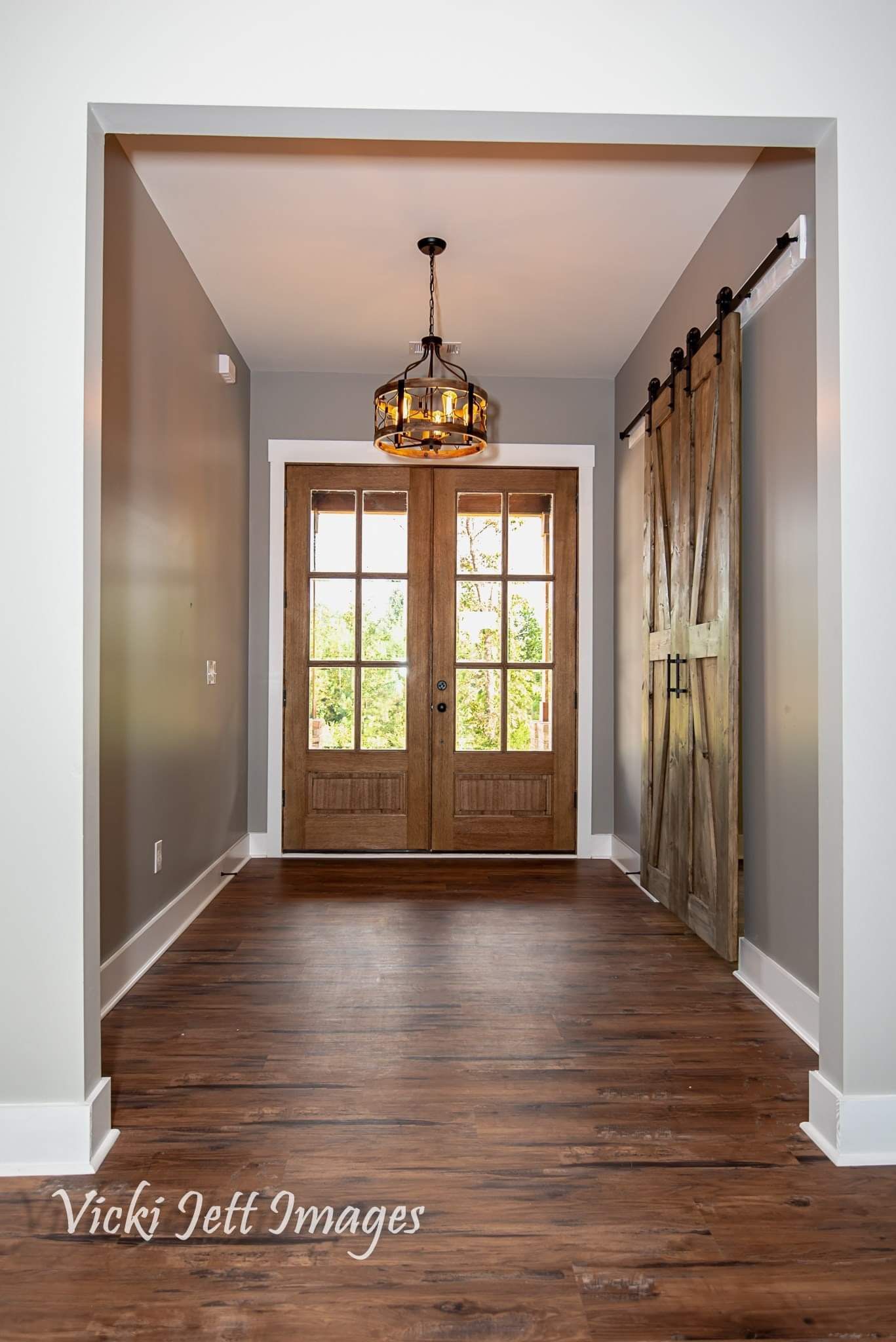 A hallway with a wooden door and a sliding barn door.