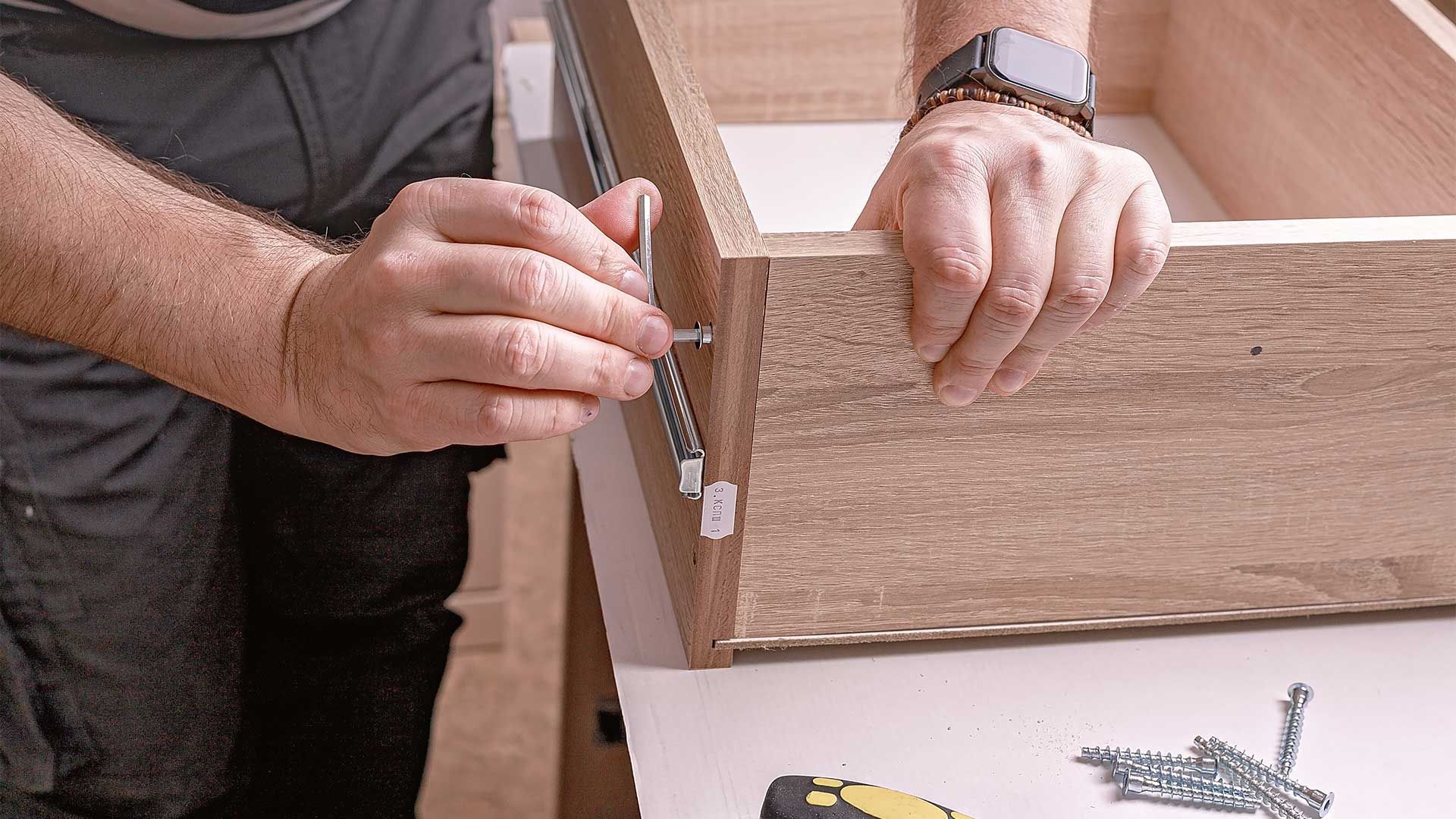 A man is screwing a screw into a piece of wood.