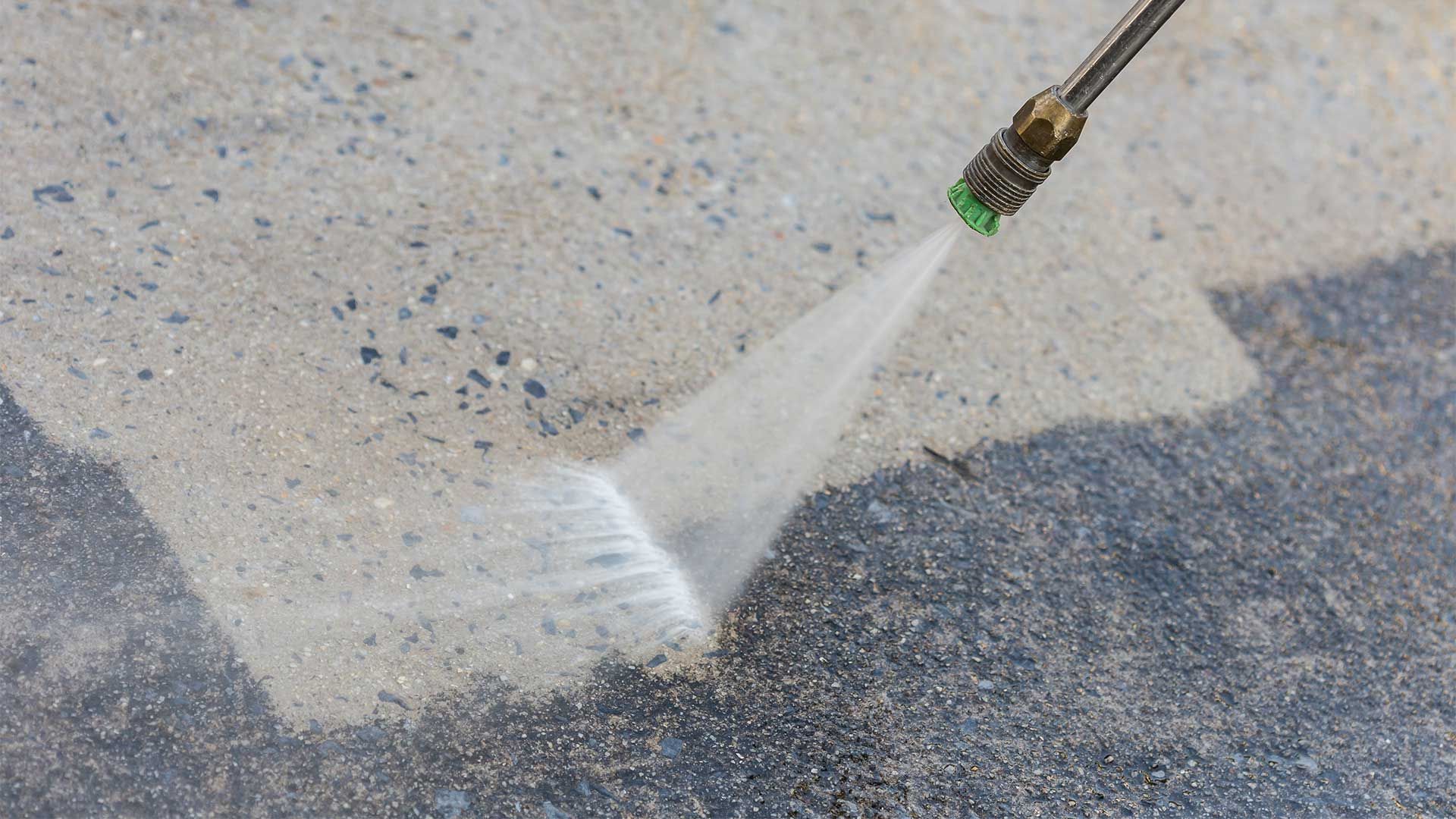 A person is using a high pressure washer to clean a concrete floor.