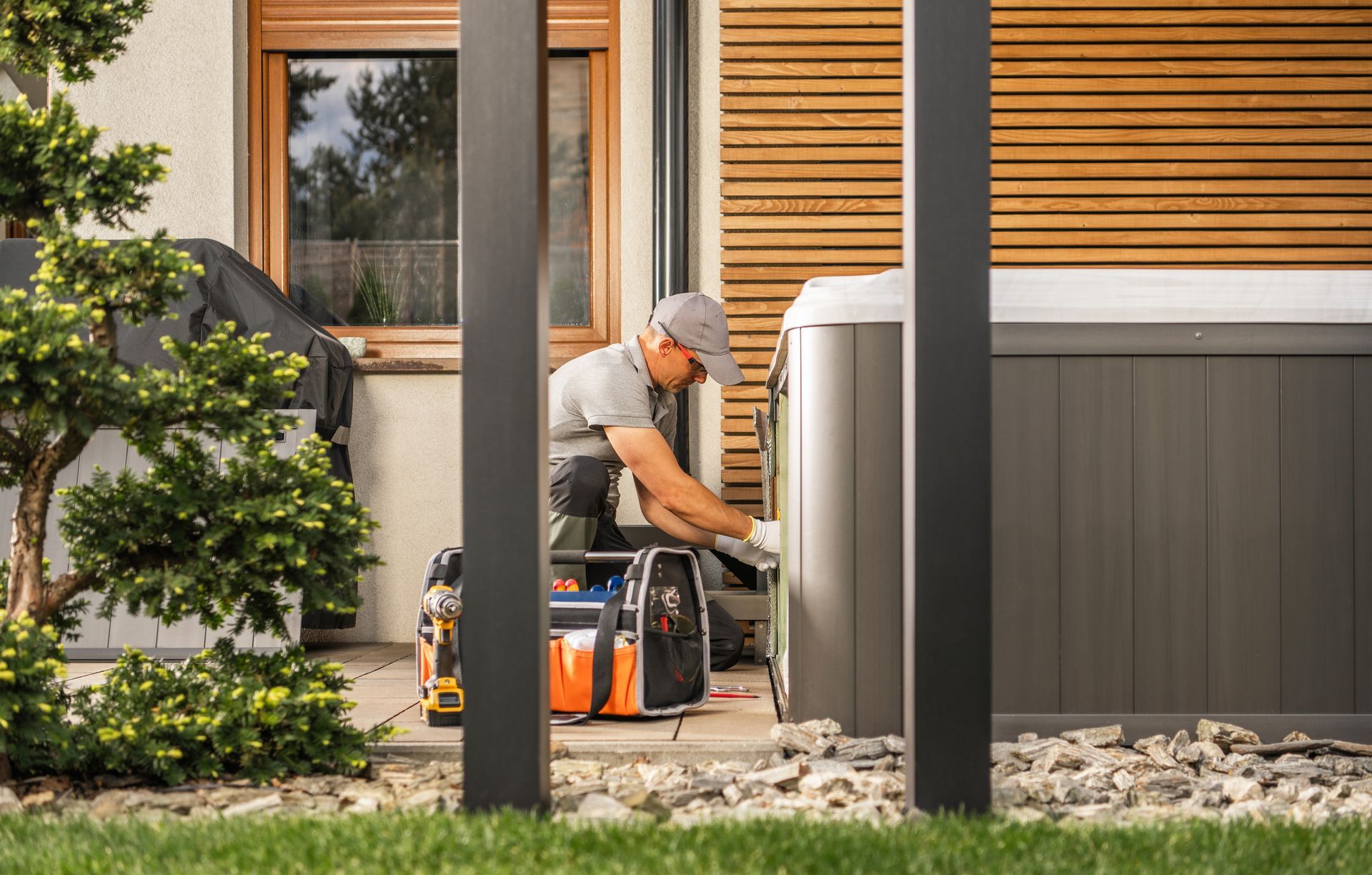 A man is working on a hot tub outside of a house.