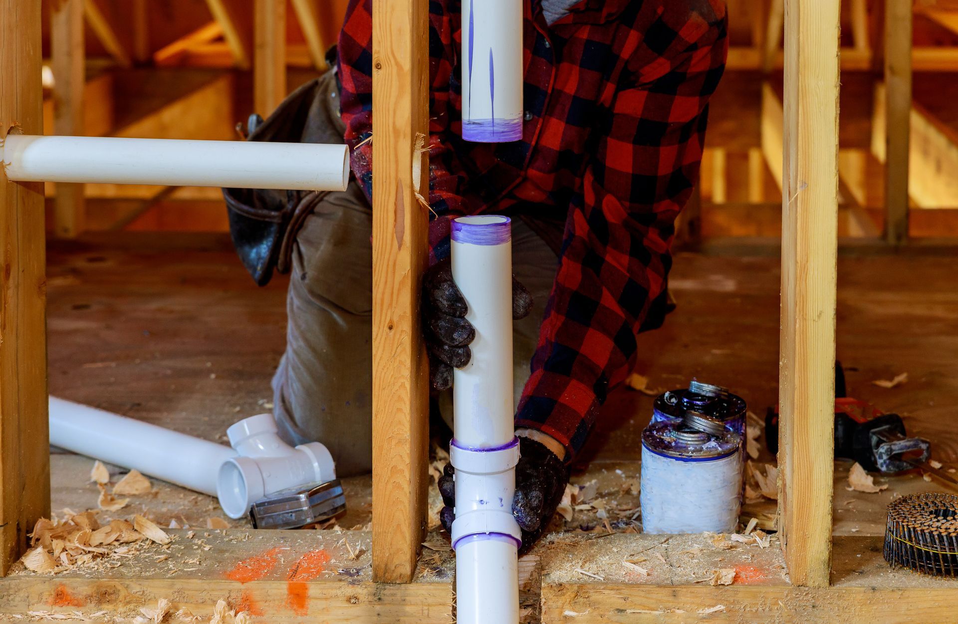 A man is working on a pipe in a house under construction.