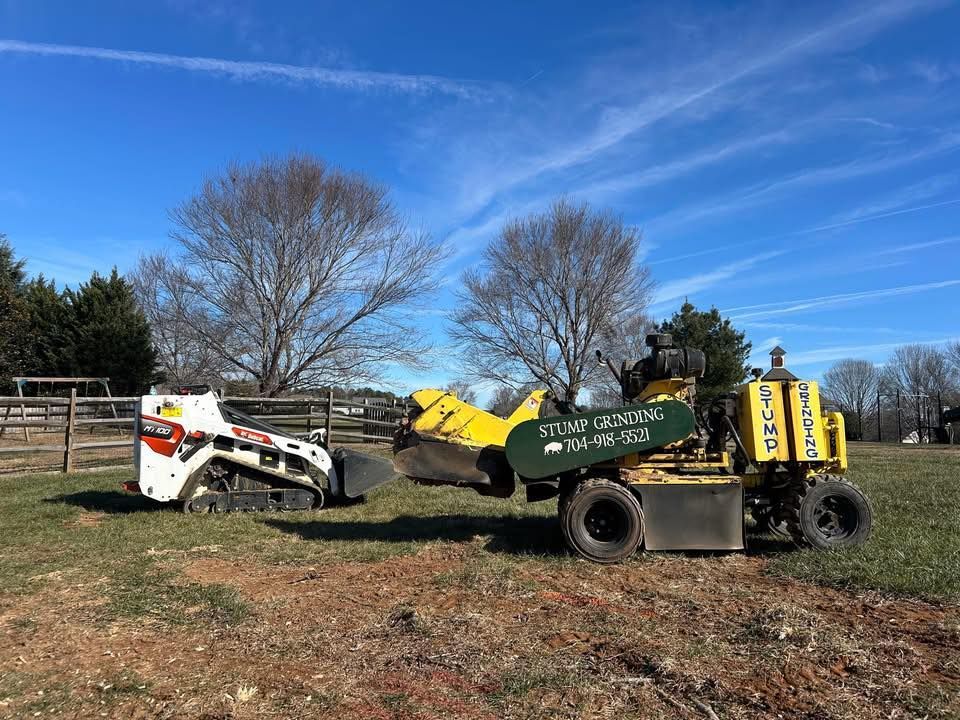 Yellow and white skid-steer loaders in a grassy field under a blue sky