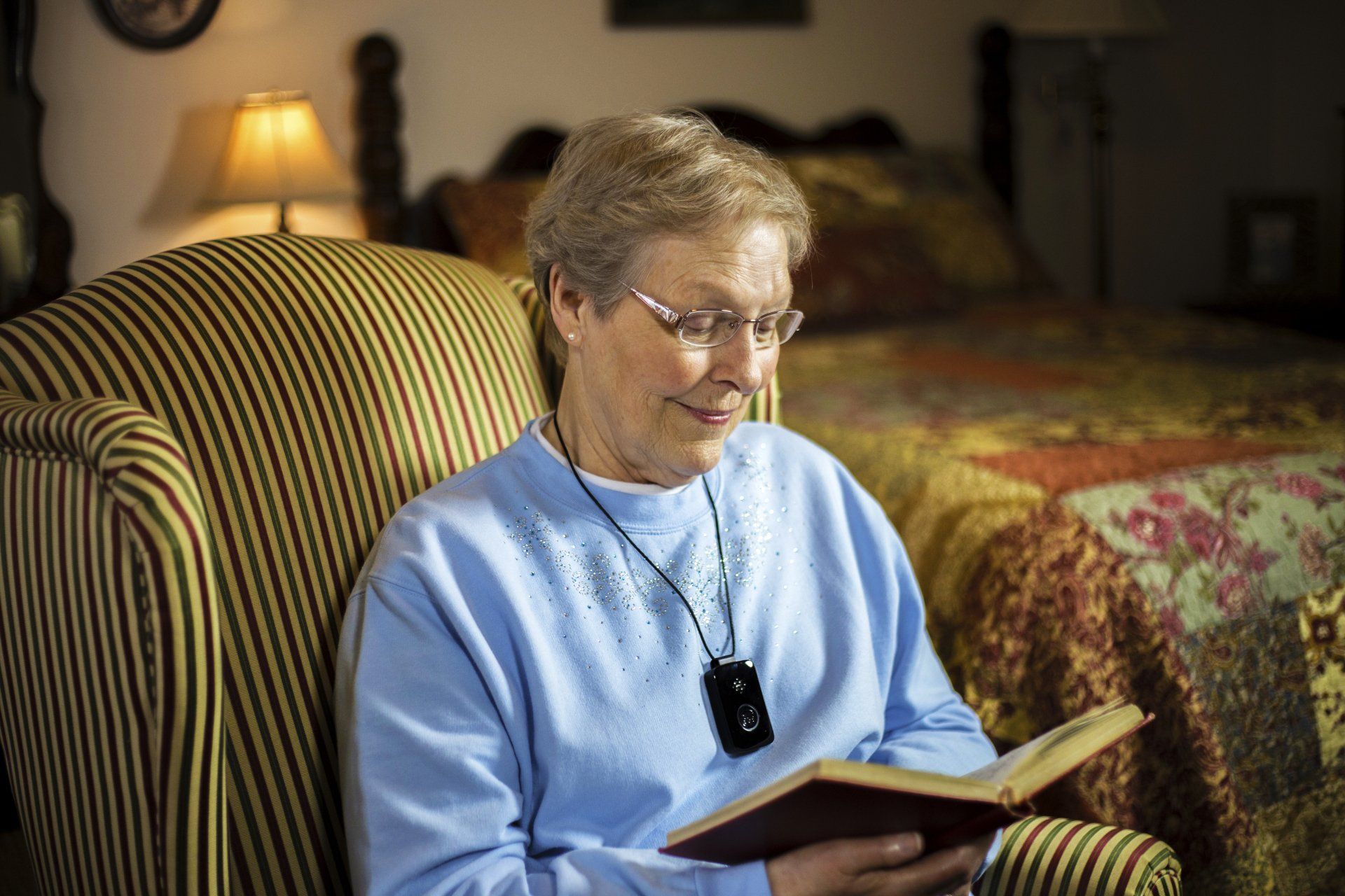 An elderly woman sits in a chair reading a book