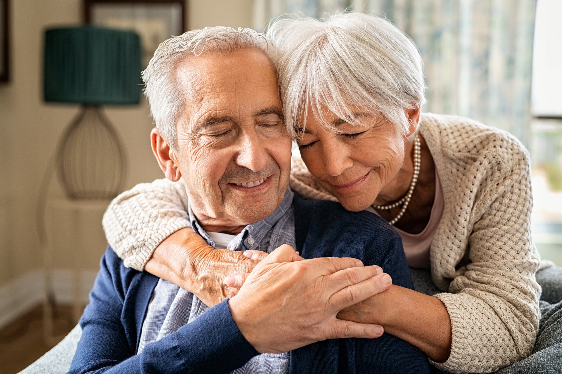 A woman is hugging an older man on a couch.