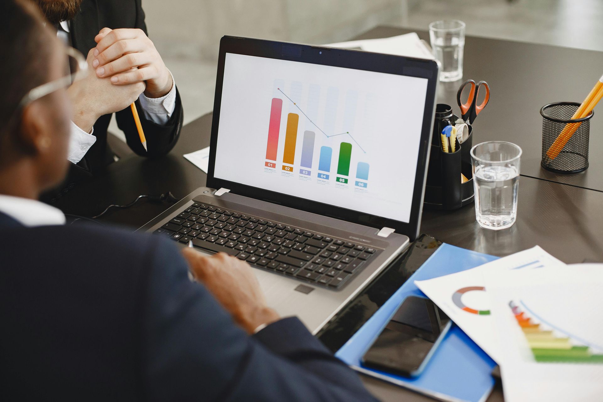 Business meeting with laptop displaying colorful bar chart and documents on a desk