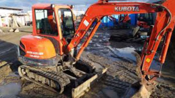 Pelle mécanique Kubota orange sur un chantier boueux, godet déployé
