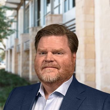 Portrait of a man in a navy suit standing outdoors in front of a building