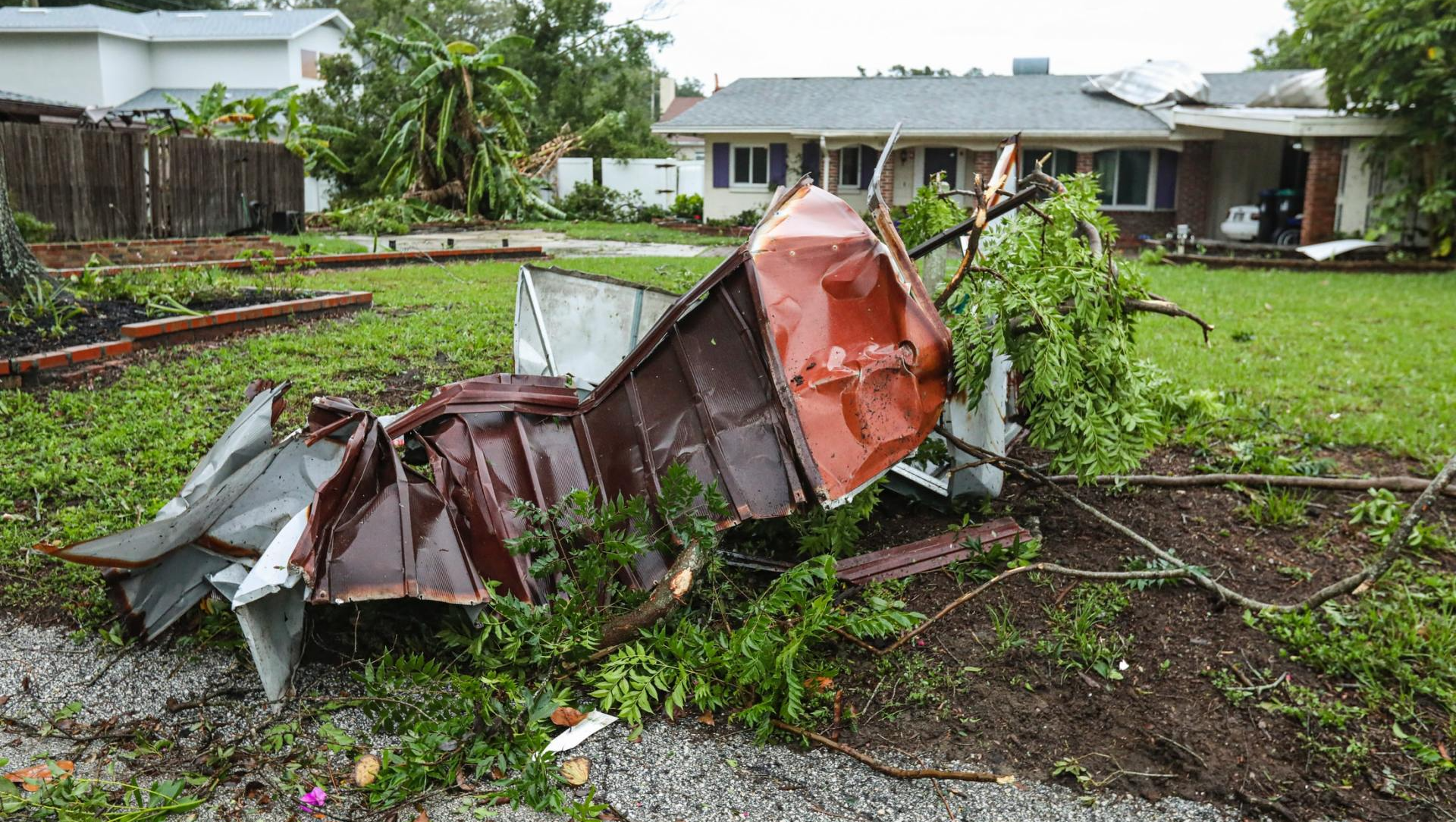 A roof is laying on the ground in front of a house.