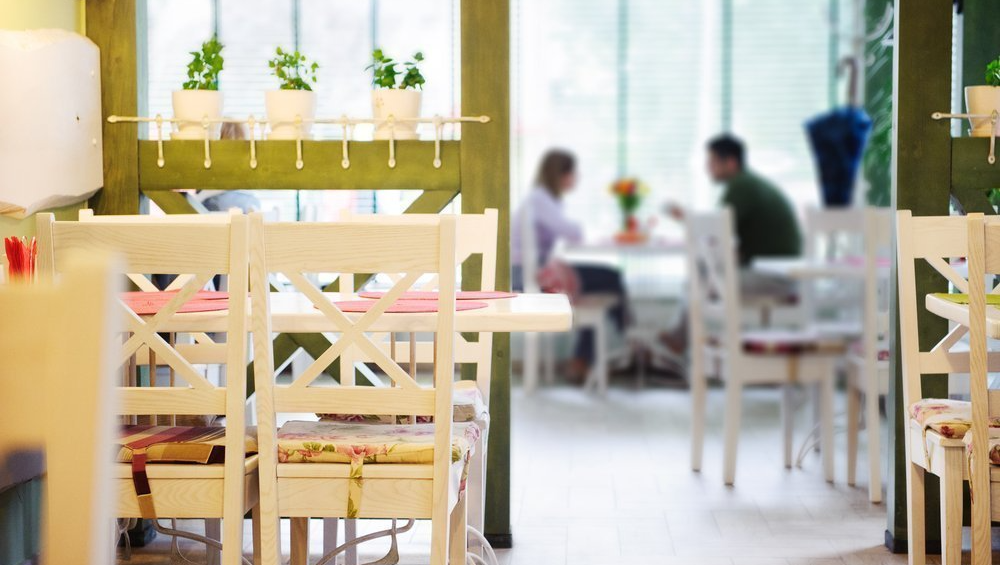 A restaurant with tables and chairs and people sitting at them.