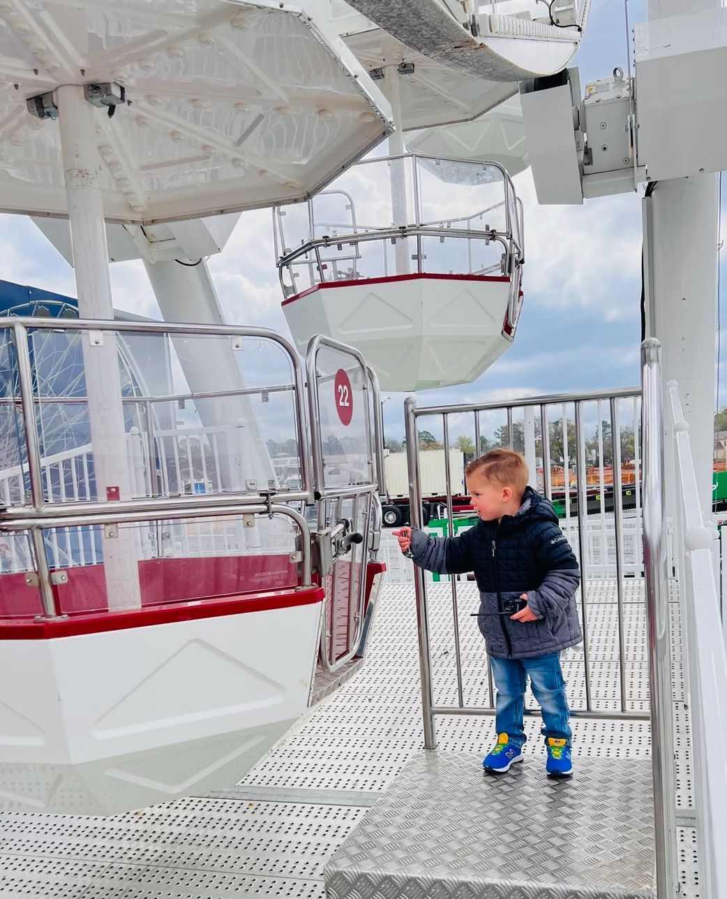 A little boy is standing in front of a ferris wheel