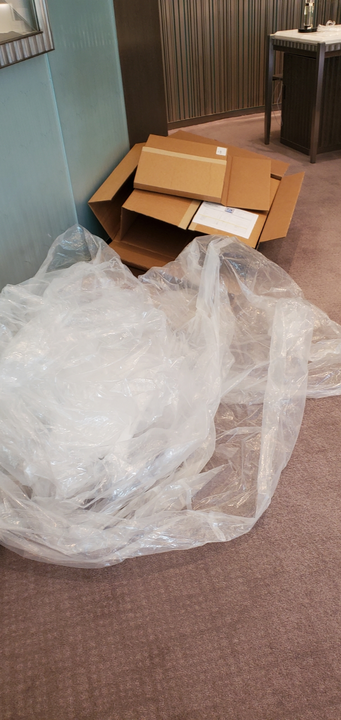 Cardboard box and bubble wrap on a brown carpet in a room.