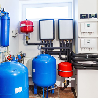 Water heating system with blue and red tanks, black pipes, and white control panels.