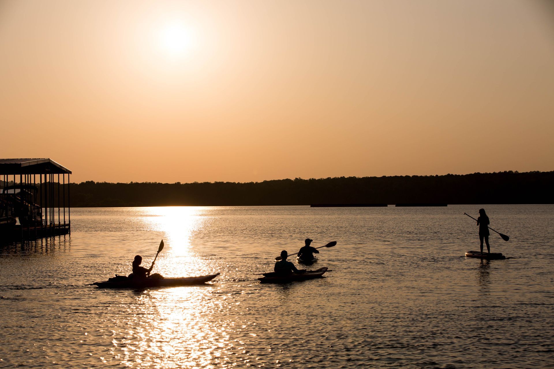 A group of people are kayaking on a lake at sunset.