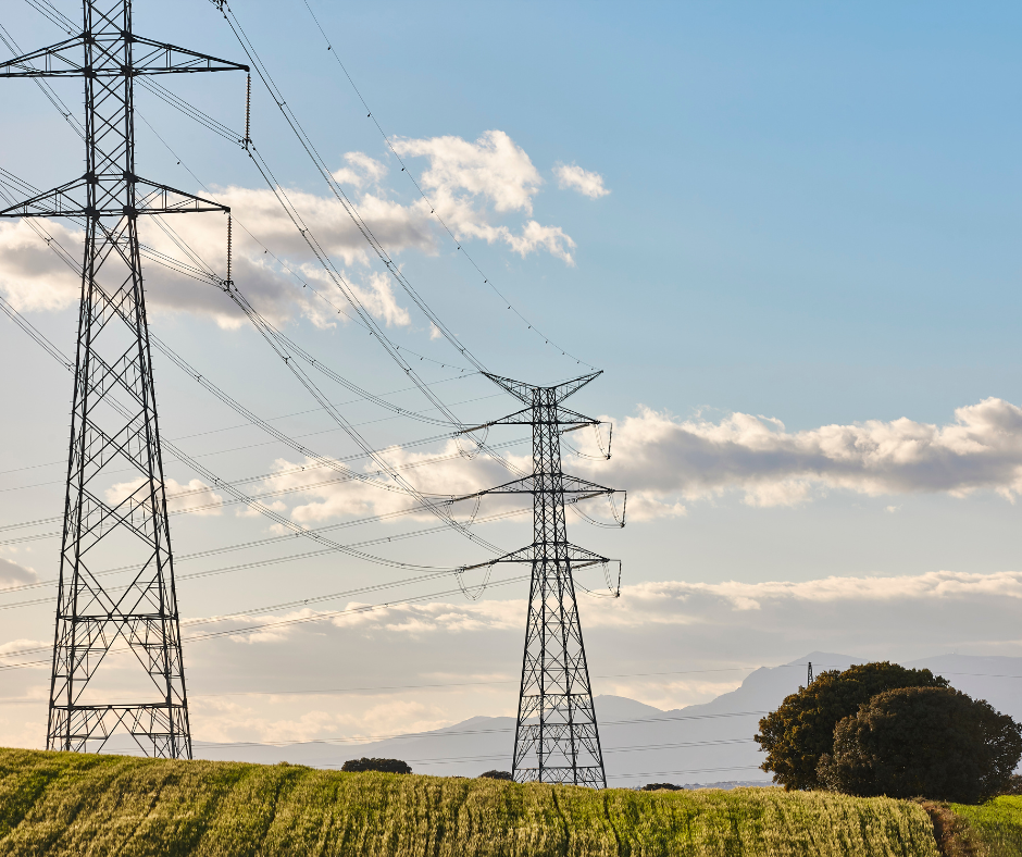 Two power lines in a field with mountains in the background