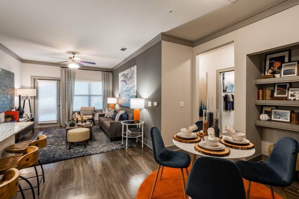 Modern apartment interior: living and dining areas, dark wood floors, blue and orange accents at Marquis Seven Meadows, offering apartments in Katy, TX.
