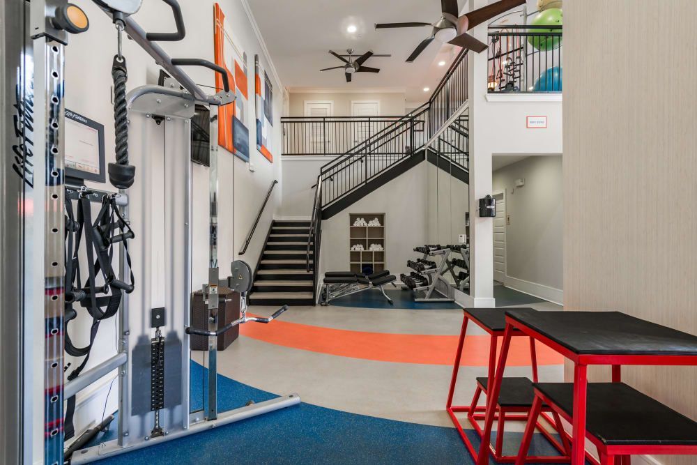 Gym interior with weight machine, stairs, and fitness equipment at Marquis Seven Meadows, offering apartments for rent in Katy ISD.