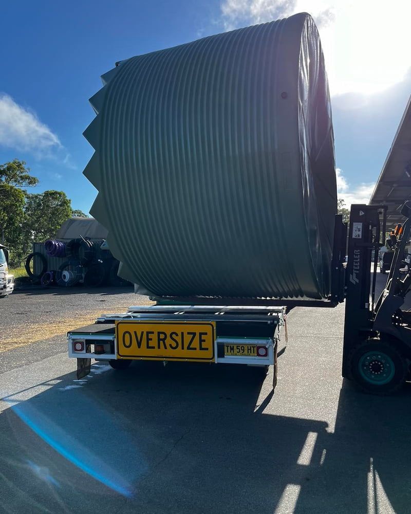 A Large Green Water Tank is Lifted by a Forklift — Gloucester Rural Supplies in Bulahdelah, NSW
