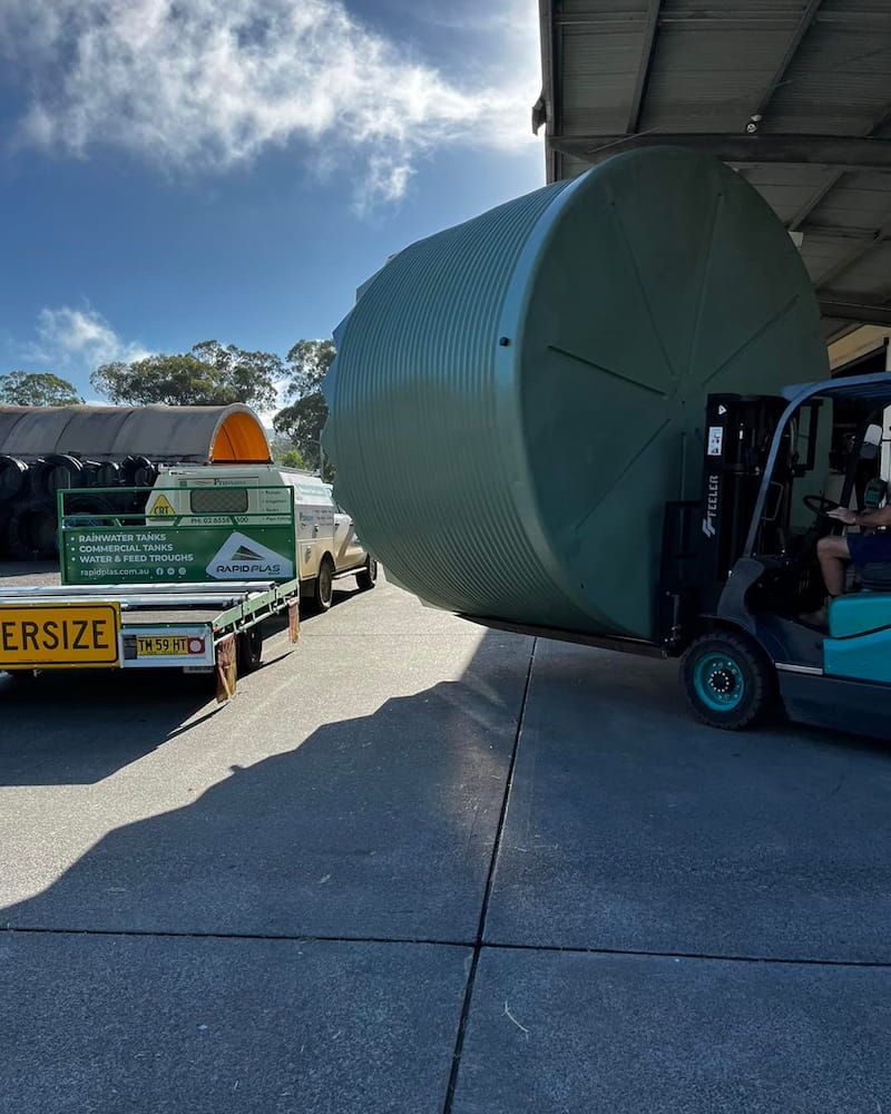 Large Green Water Tank Loaded Onto Truck With Forklift on Sunny Day — Gloucester Rural Supplies in Stroud, NSW