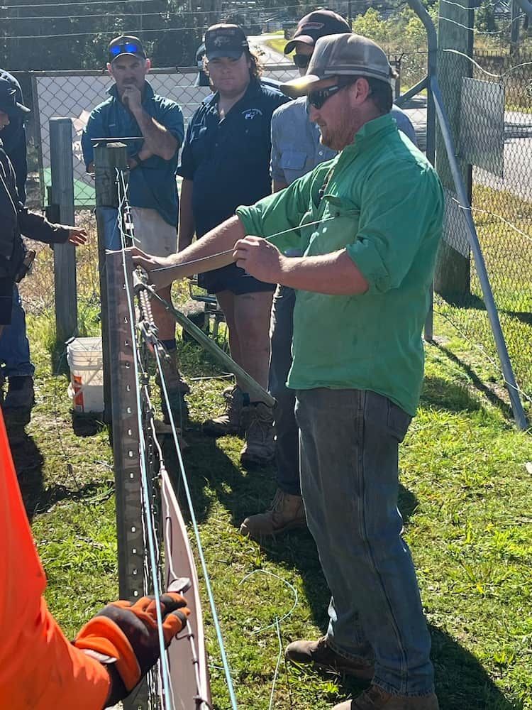 Man in Green Demonstrates Wire Fence Construction to Group Outside — Gloucester Rural Supplies in Stroud, NSW