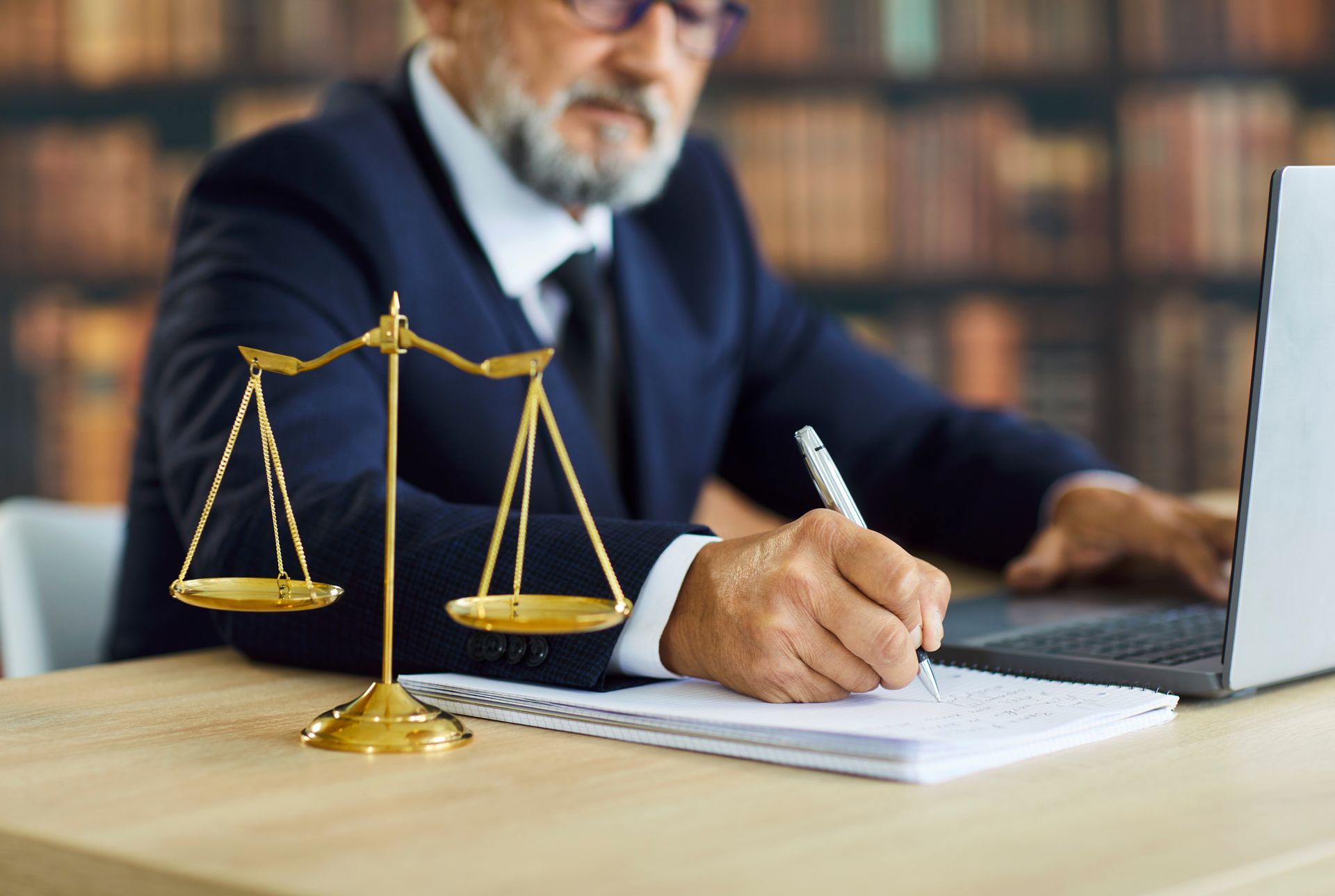 Criminal defense attorney reviewing case files next to scales of justice in a law library. Criminal defense attorney reviewing case files next to scales of justice in a law library.