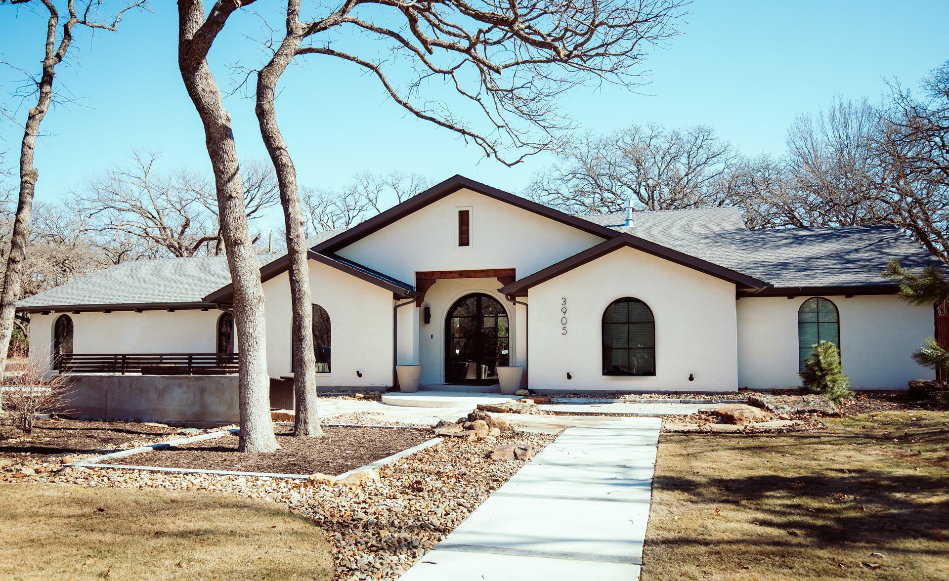 A large white house with a black roof and a driveway