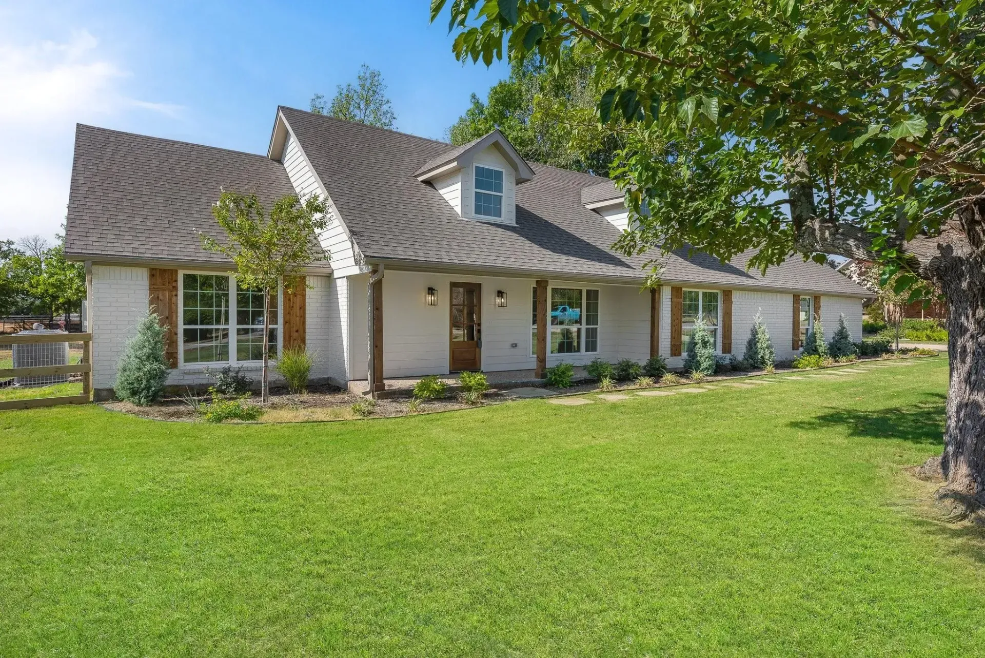 A large white house with a black roof and a driveway