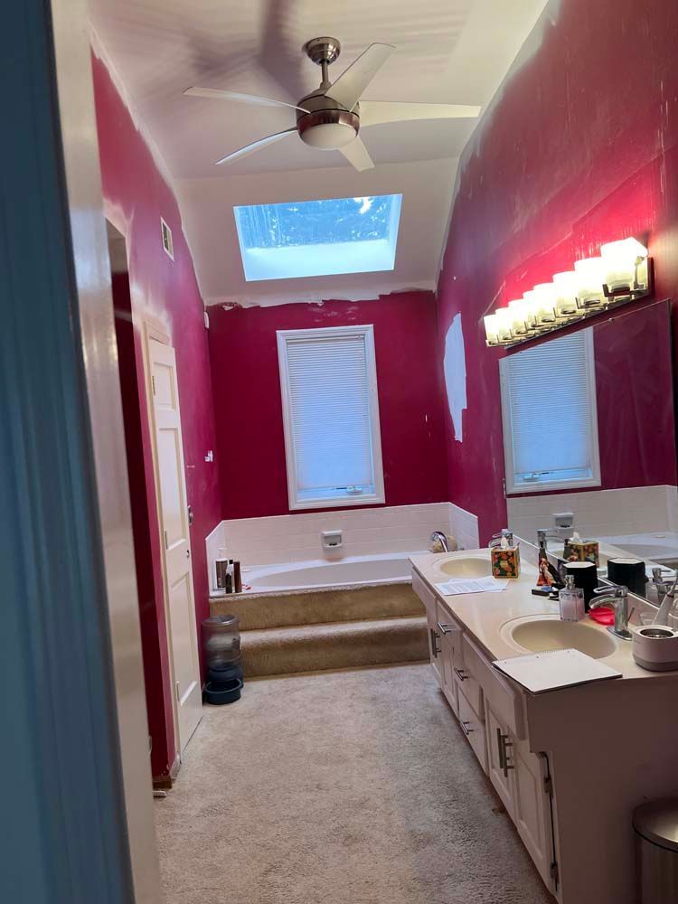 Pink bathroom with a skylight, white vanity, bathtub, and mirror lights