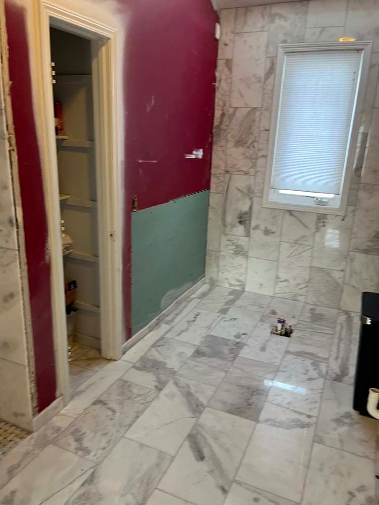 Renovated hallway with marble-pattern tile floor, red and green walls, and a small window at the end.