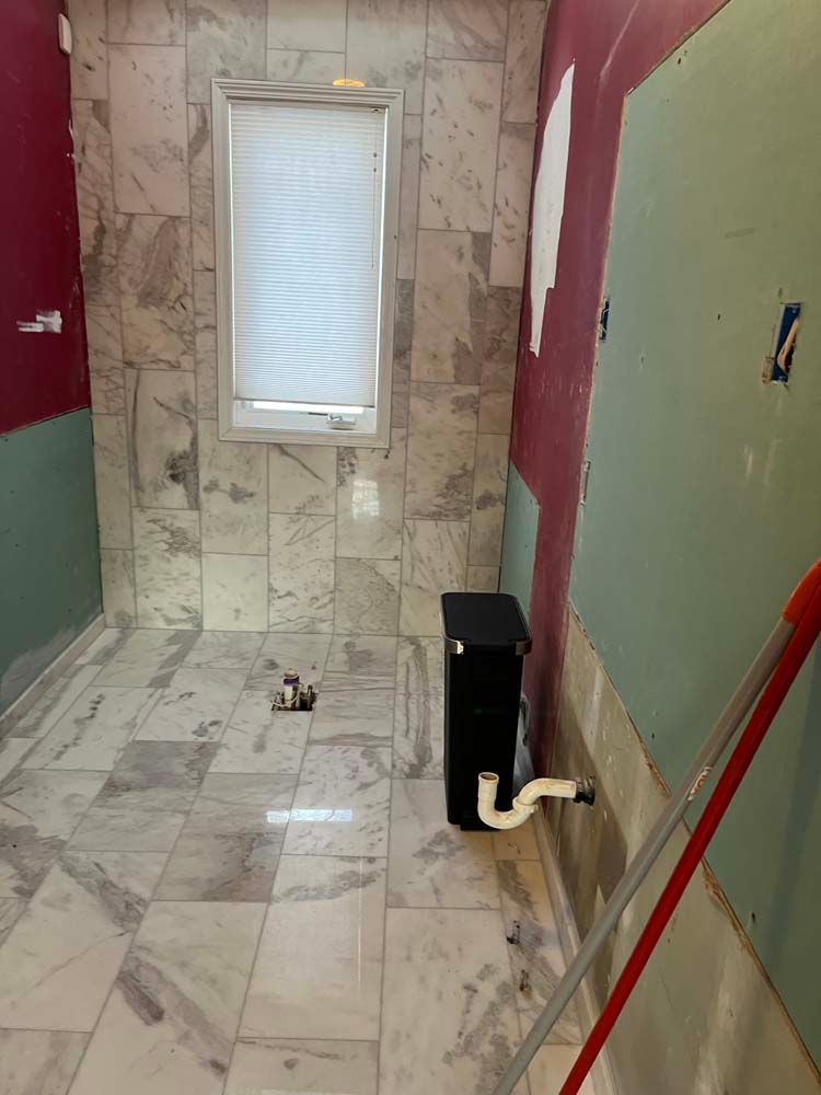 Narrow tiled hallway with a small window, red and green walls, and a black utility box near the floor.