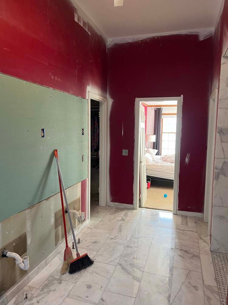Partially renovated hallway with red walls, tiled floor, and a broom leaning against the wall