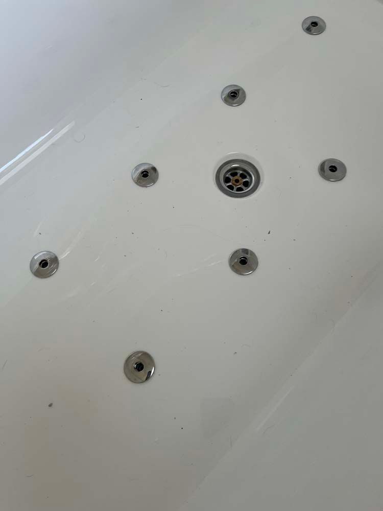 White bathtub interior with multiple metal jet nozzles and a center drain.