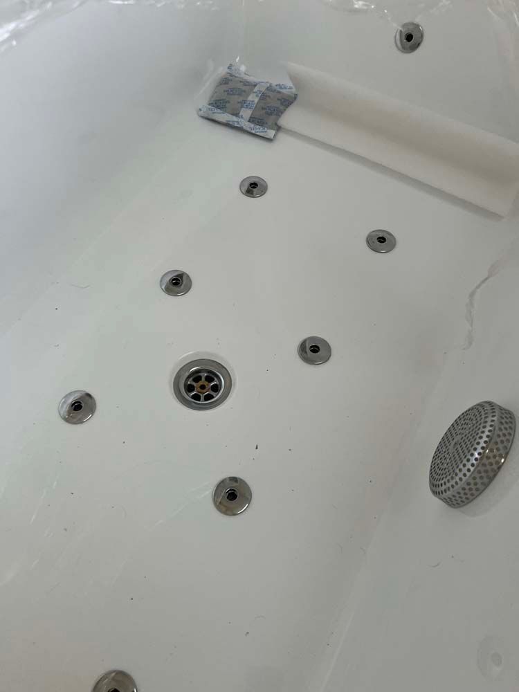 White bathtub interior with multiple jets, a drain, and a faucet handle near the top.