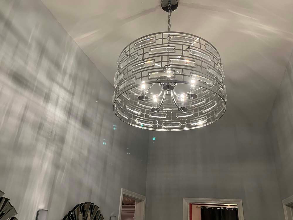 Modern chandelier hanging from a high white ceiling in a bright room