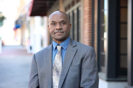 A man in a suit and tie is standing in front of a building.