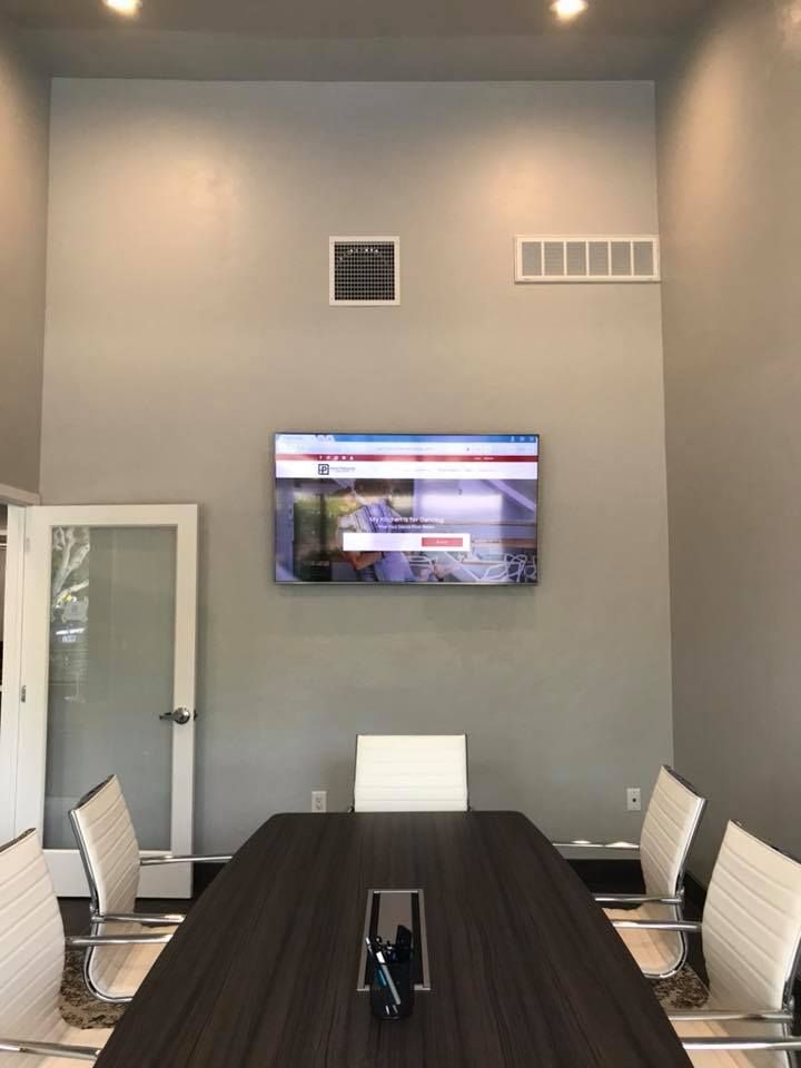 A conference room with a table and chairs and a flat screen tv on the wall