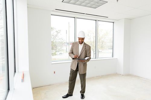 A man is using his tablet in an office that is under construction. A man is using his tablet in an office that is under construction.