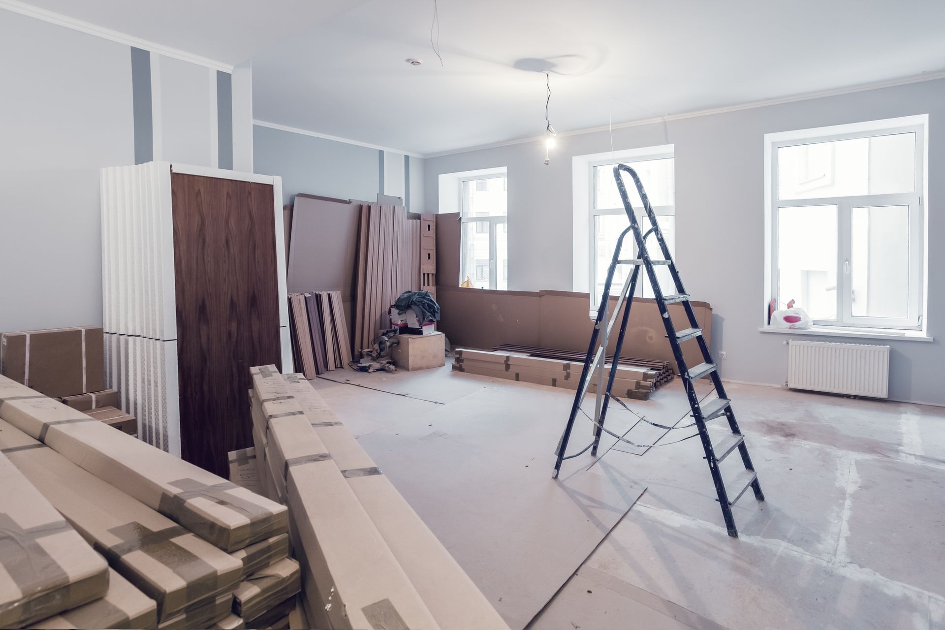 Interior of apartment with wooden planks and other materials, as well as stepladders.