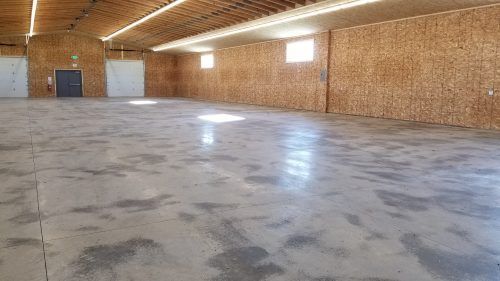 Empty brick-walled hall with a concrete floor and arched wooden ceiling