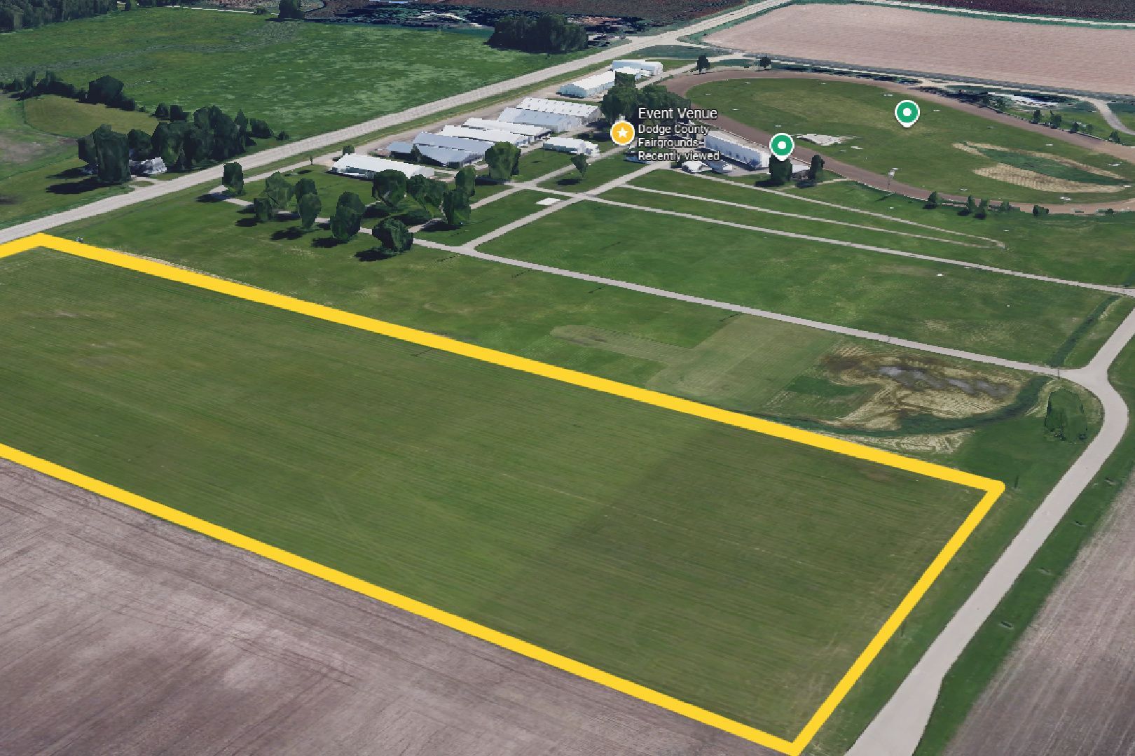 Aerial view of a farm field outlined in yellow near buildings and roads.