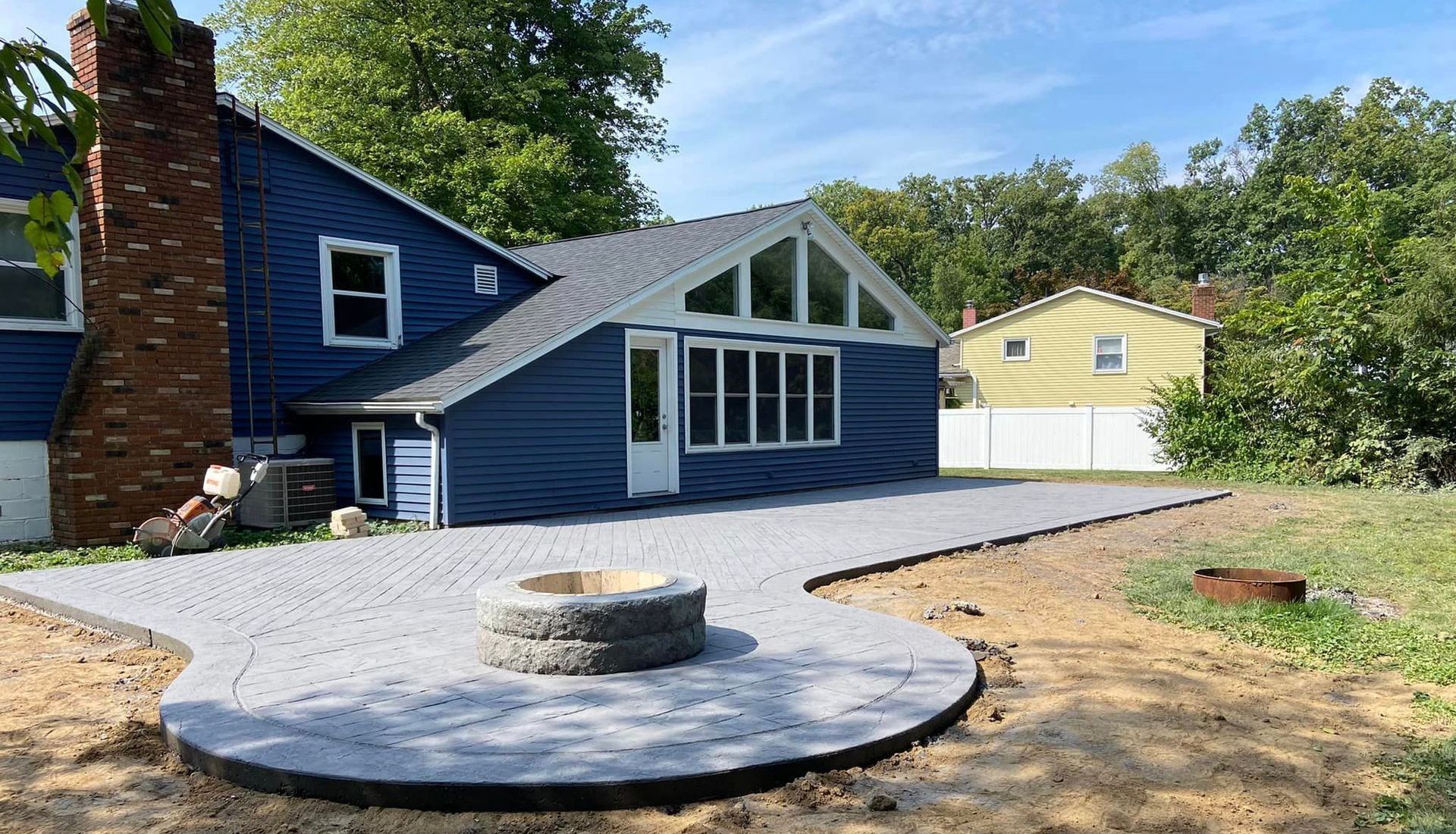 A blue house with a fire pit in front of it.