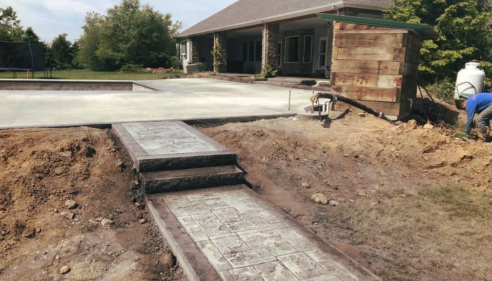 A concrete walkway is being built in front of a house.