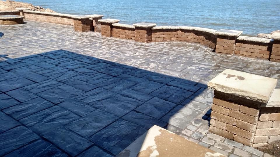 A patio with a view of the ocean and a brick wall.