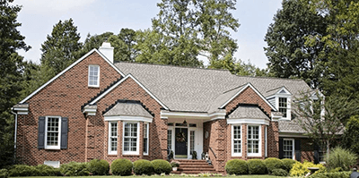 Brick suburban house with white trim, gabled roof, and a landscaped front yard