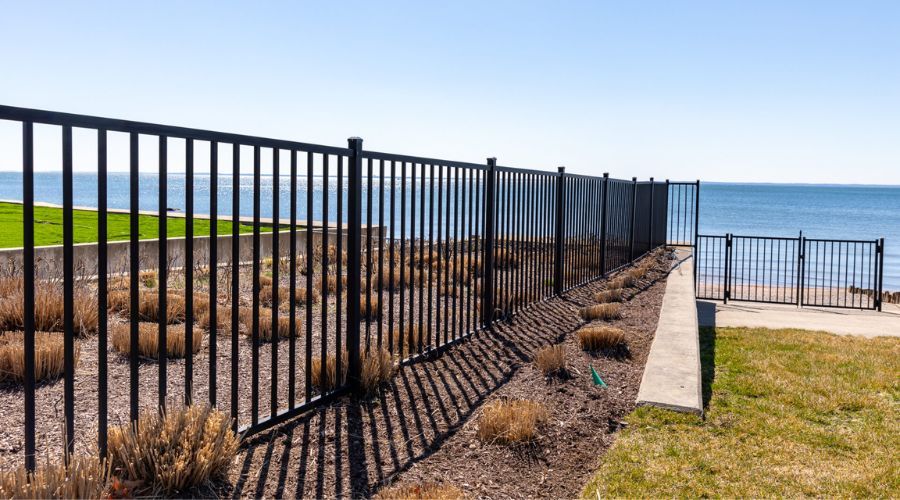 Black aluminum coastal fence and walk gate installed along a waterfront property overlooking the oce