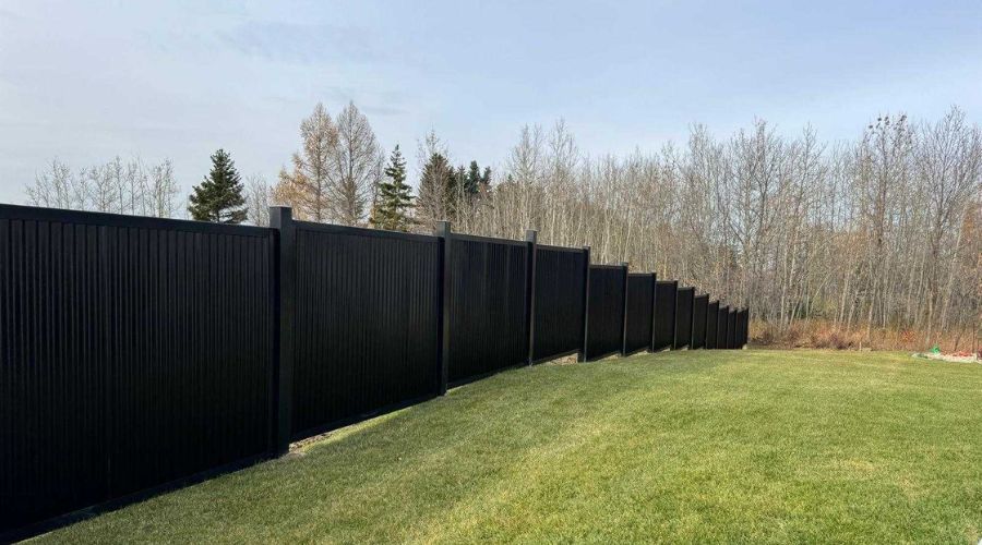 Black privacy fence installed along a spacious green backyard