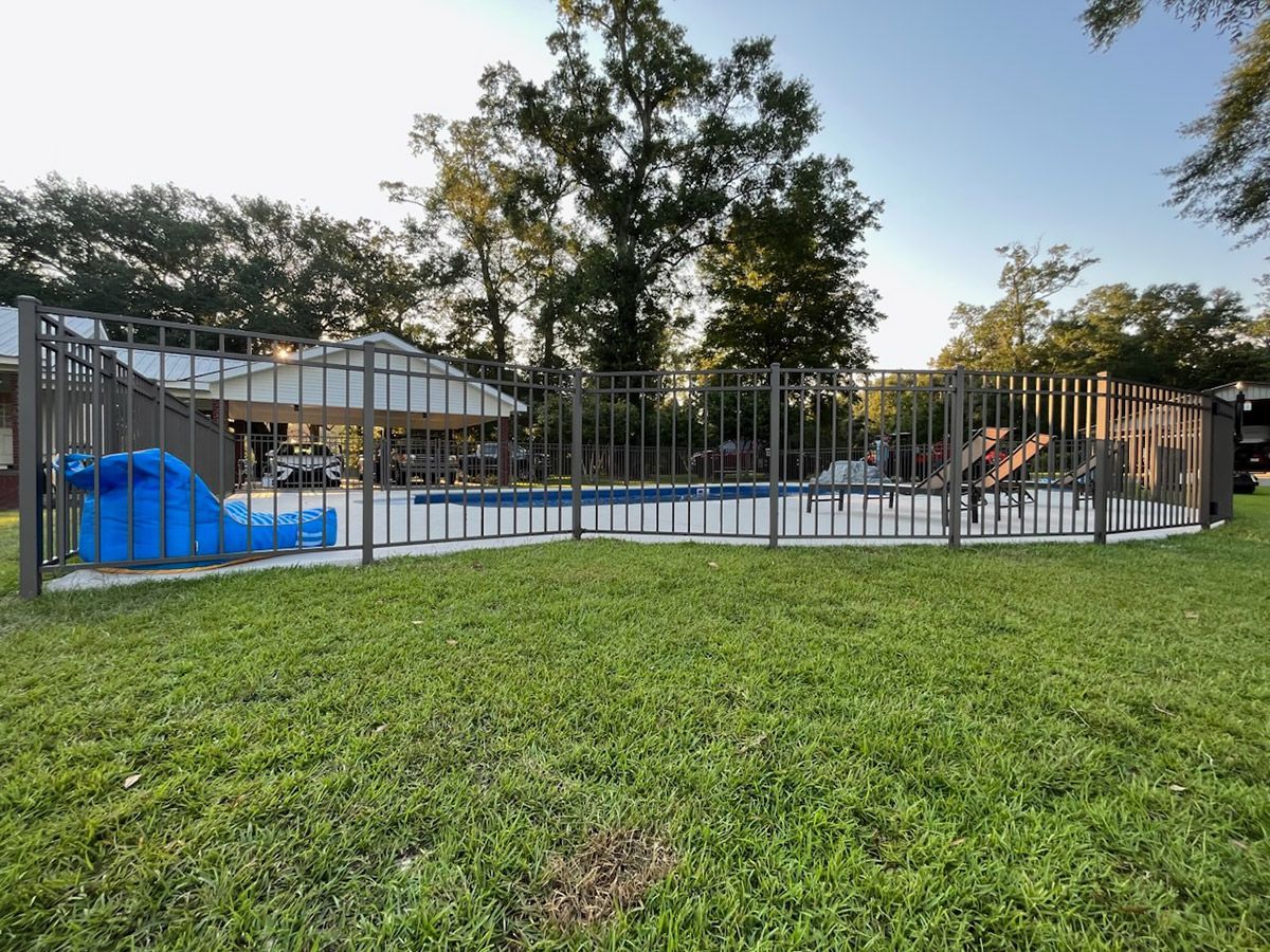 A fence surrounds a swimming pool in a backyard.