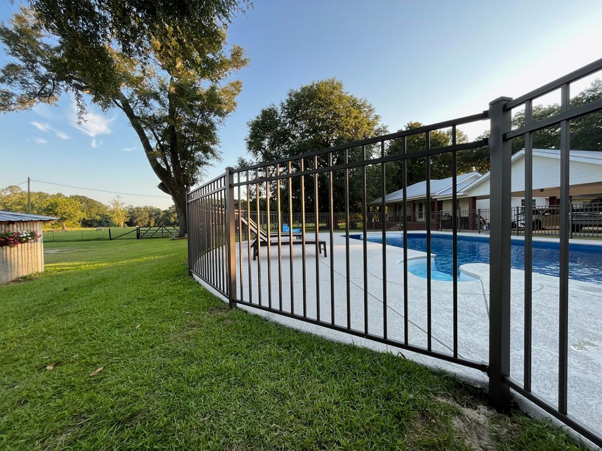 A metal fence surrounds a swimming pool in a backyard.